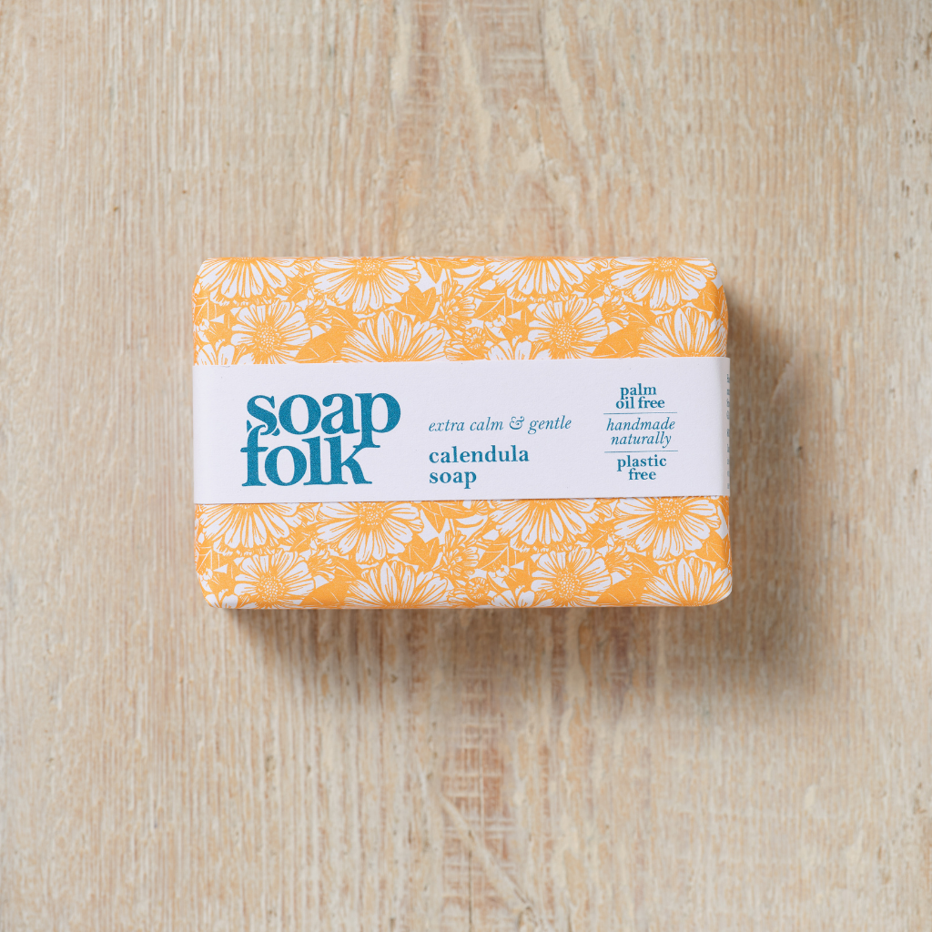 Bar of Calendula soap with 'soap folk' branding on a wooden surface