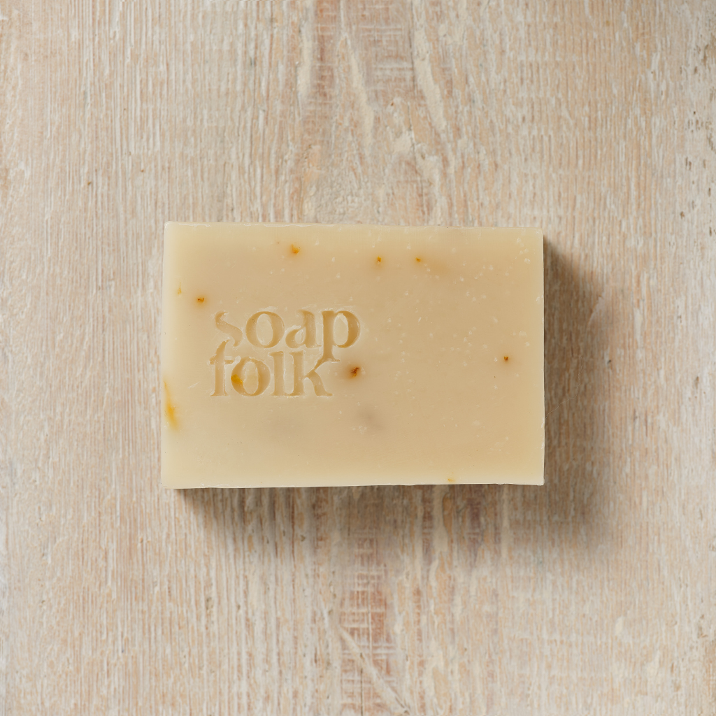 Bar of Calendula soap with 'soap folk' branding on a wooden surface