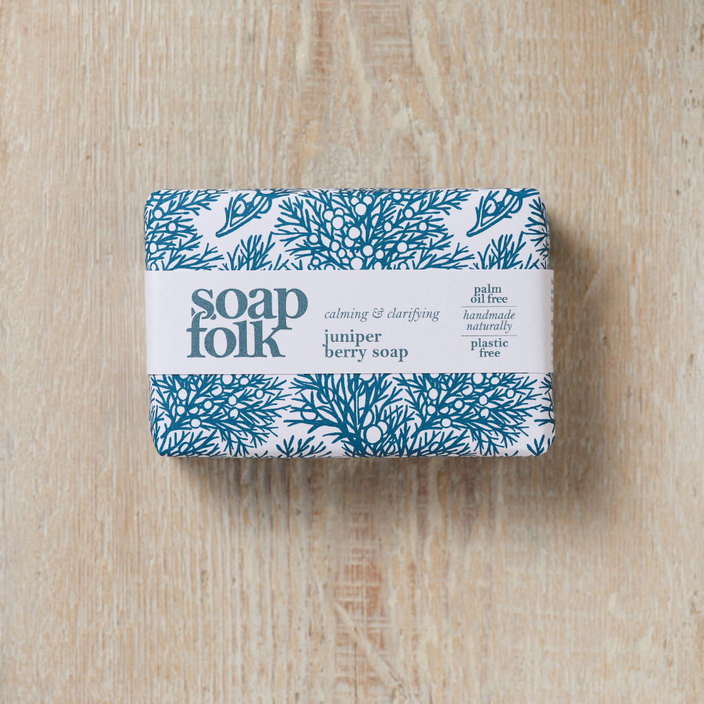 Bar of  Juniper Berry soap with 'Soap Folk' packaging on a wooden surface