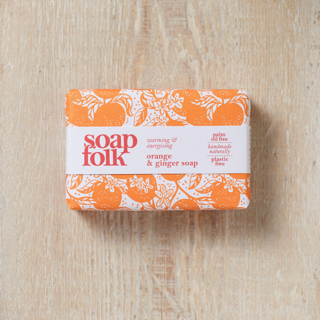 Bar of Orange and Ginger soap with 'Soap Folk' packaging on a wooden surface