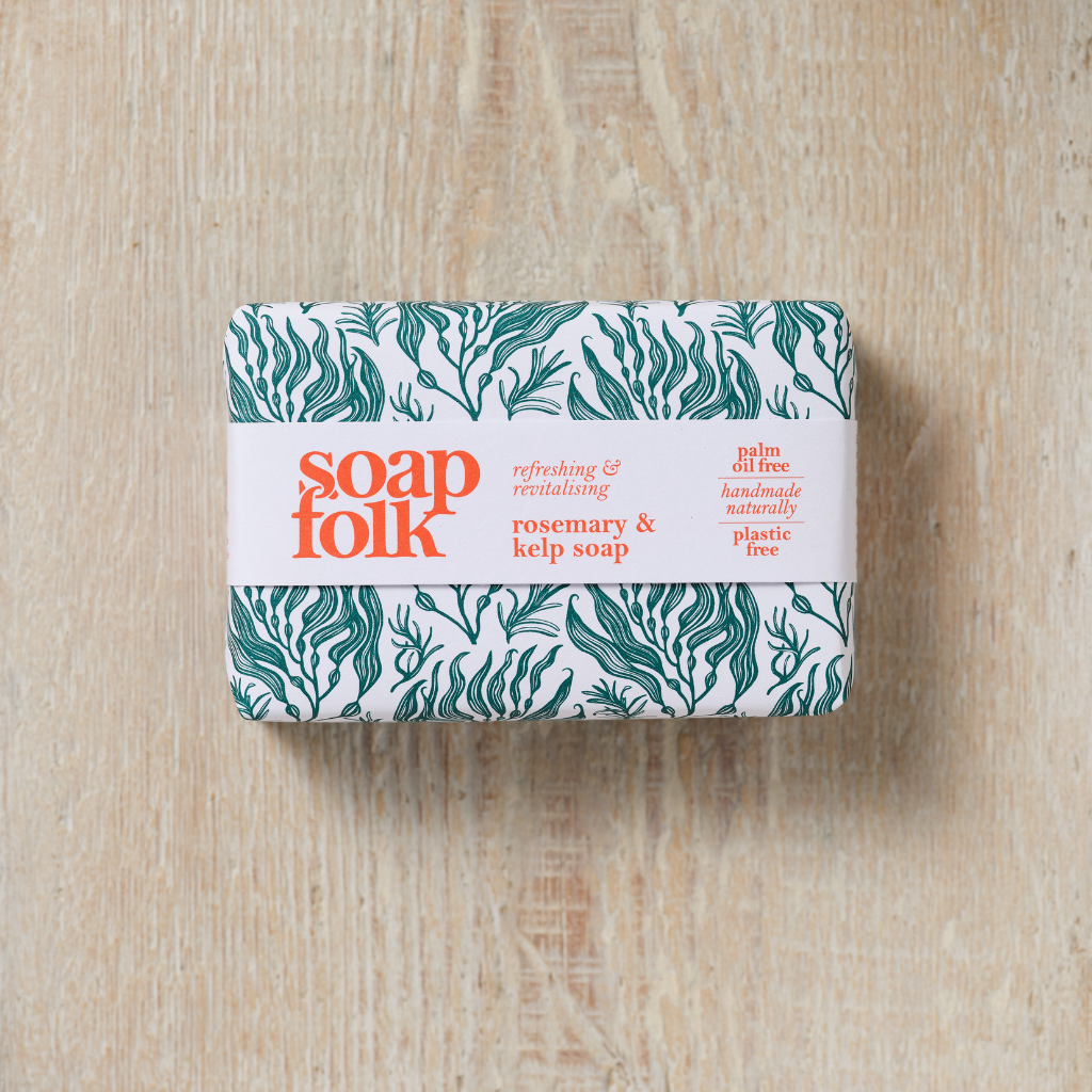 Bar of Rosemary and Kelp soap with 'soap folk' packaging on a wooden surface