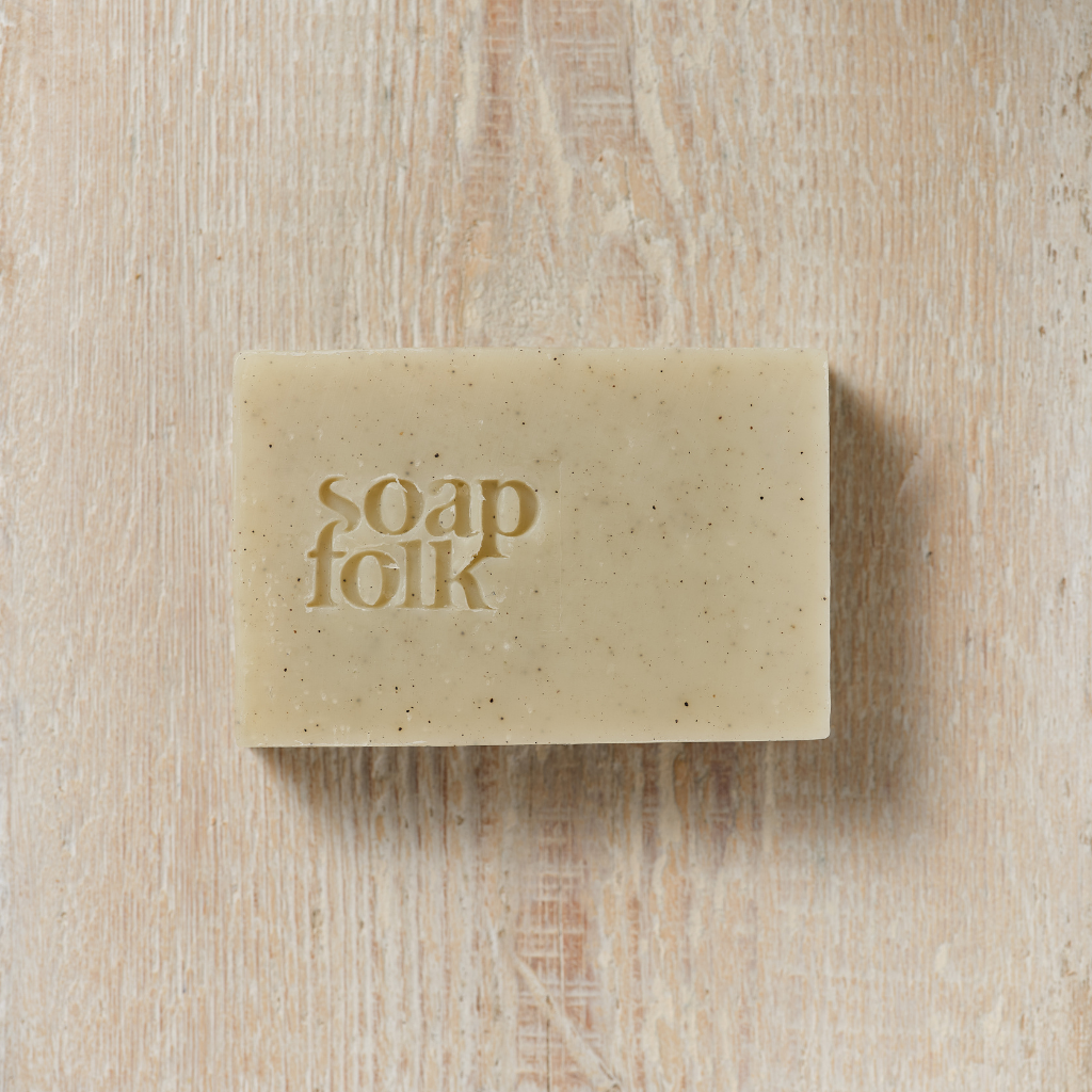 Bar of Rosemary and Kelp soap with 'soap folk' packaging on a wooden surface