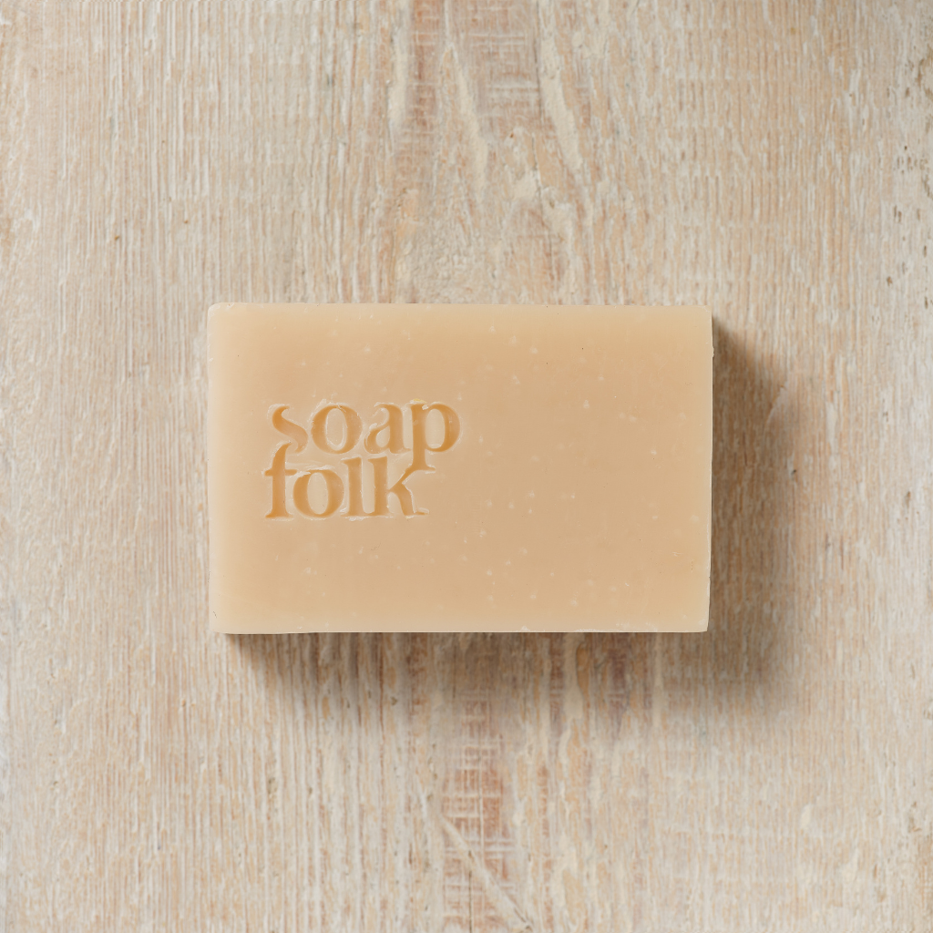 Bar of  Rose Geranium soap with 'soap folk' branding on a wooden surface