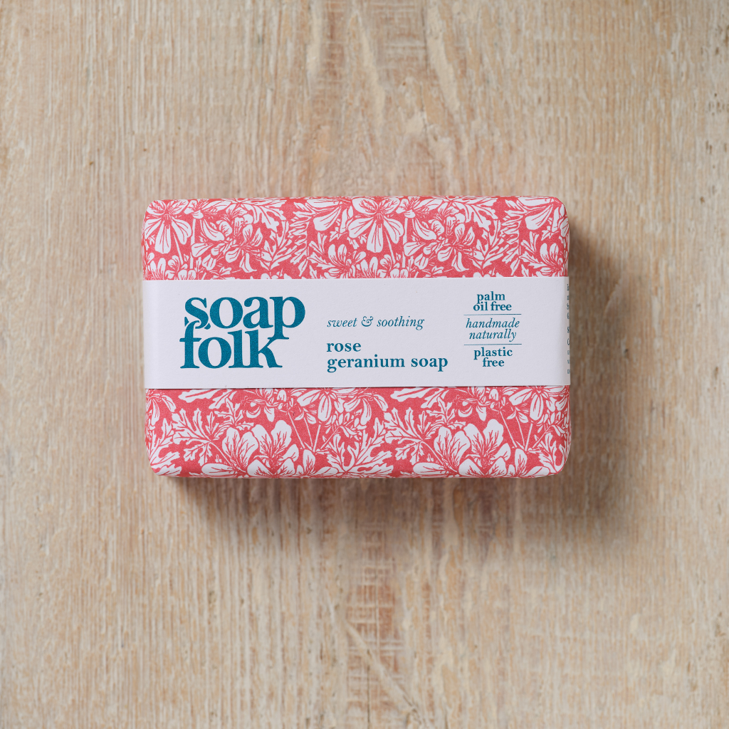 Bar of  Rose Geranium soap with 'soap folk' branding on a wooden surface