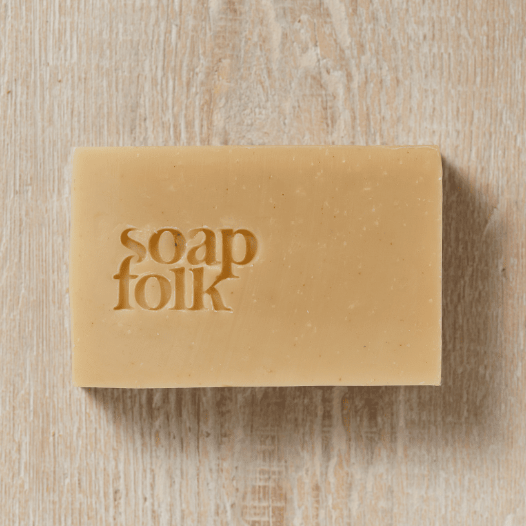 Unwrapped bar of Juniper Berry soap with 'soap folk' embossed in the bar. Sat on a wooden surface.