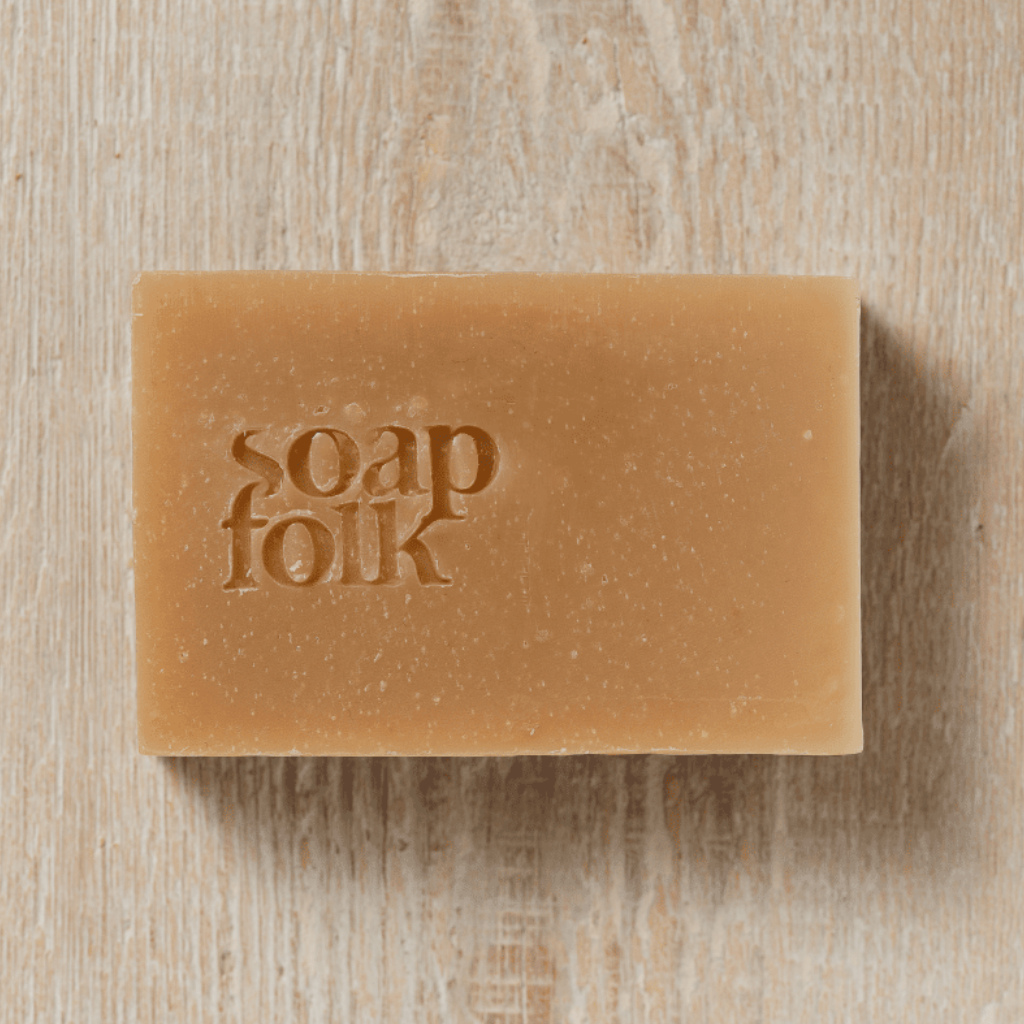 Bar of unwrapped Spiced Apple soap with 'soap folk' embossed in the bar. Sat on a wooden surface.